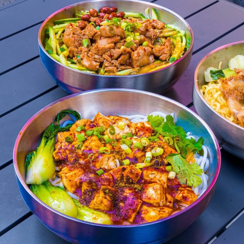 Three bowls of Loong Noodles dishes, including one with chicken, one with tofu and bok choy.
